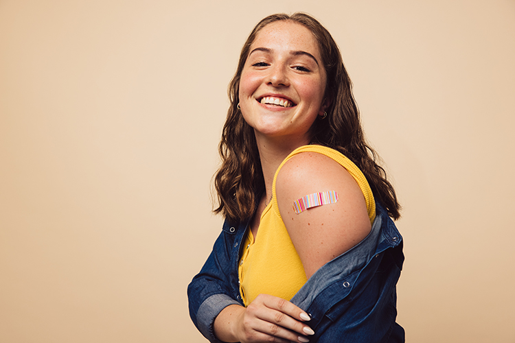 Young woman smiling and showing vaccination.